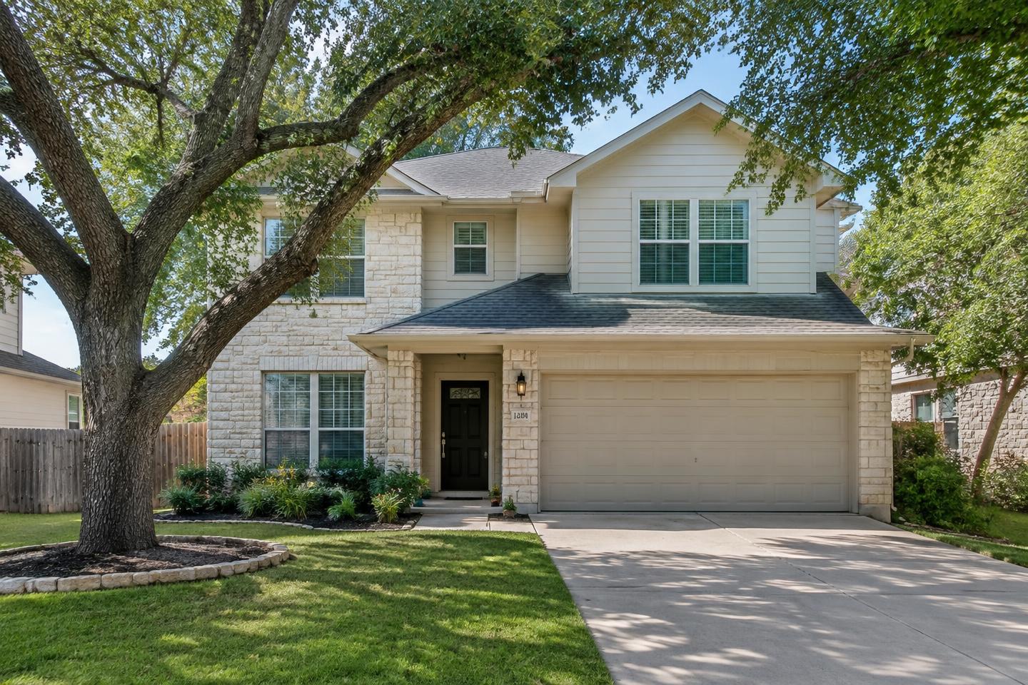 Well-kept limestone family home beneath mature live oak trees in Westlake